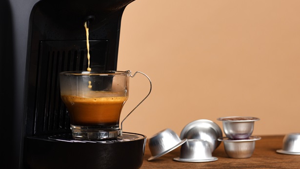 Chávena transparente debaixo de uma máquina de café de cápsulas